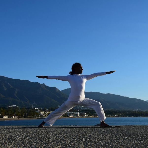 Silhouette of a person in a powerful warrior yoga pose at sunrise.